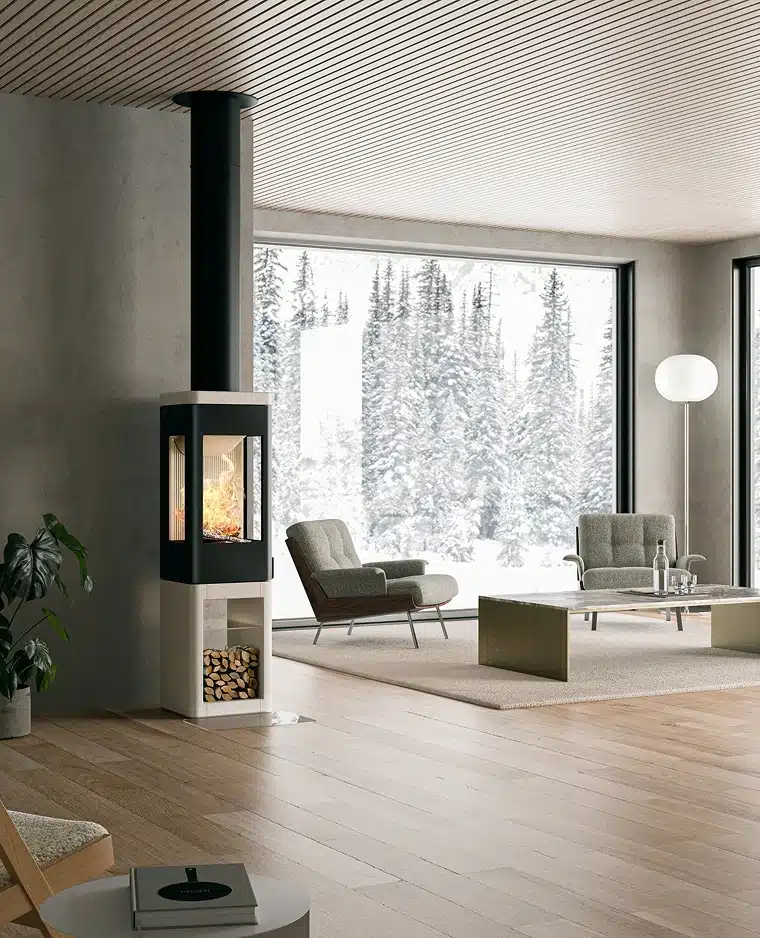 Salon moderne doté d'une cheminée à bois, de deux fauteuils, d'une table basse et de grandes fenêtres révélant un paysage de forêt enneigée à l'extérieur. L'espace présente une décoration minimaliste et un sol en bois naturel.